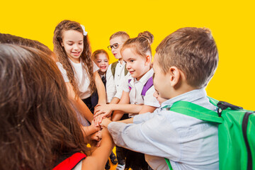 The schoolchildren are stacking hands together at the yellow background