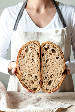 Hands holding freshly baked sourdough bread