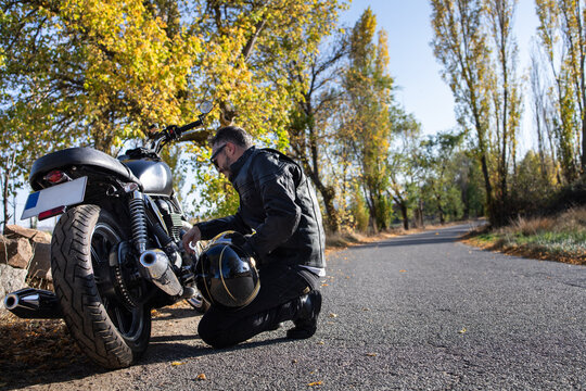 Focused Aged Male Biker Checking Motorcycle On Road In Countryside