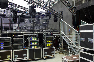 Installation of professional sound, light, video and stage equipment for a concert. Backstage area and tech zone with amplifiers, flight cases and radio microphones. - obrazy, fototapety, plakaty