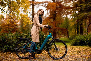 Fototapeta na wymiar Young woman with electric bicycle in te autumn park