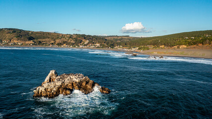 Matanzas, Chile, horizontal  aerial photo of rock in the sea with sunlight and beach