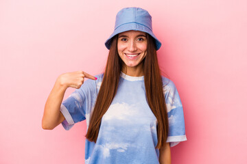 Fototapeta premium Young caucasian woman isolated on pink background person pointing by hand to a shirt copy space, proud and confident