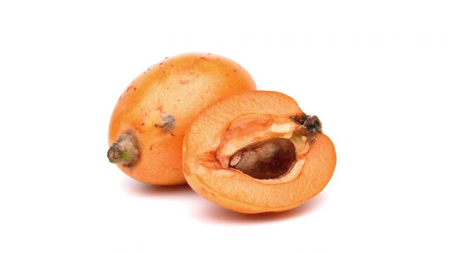 One whole and one half cut loquat fruit rotating. Isolated on white background.