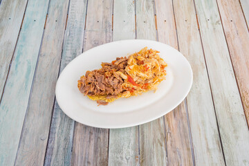 Venezuelan mixed patacon of shredded chicken and vegetables, ripe plantains and shredded beef on white plate