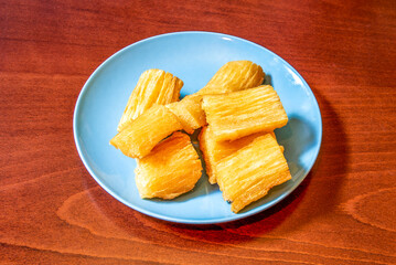 Pieces of tasty Caribbean cassava cooked and then fried in olive oil on a blue plate