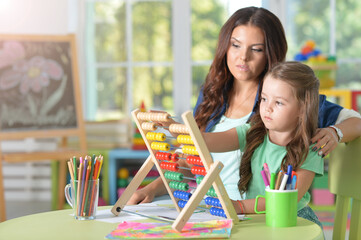 Portrait of girl with mother using abacus