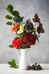 Bouquet of fresh flowers branches and black berries on table. Autumn holiday concept.