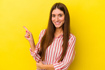 Young caucasian woman isolated on yellow background smiling cheerfully pointing with forefinger away.