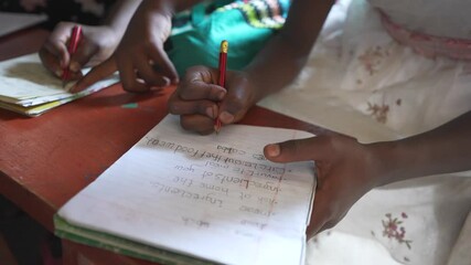 Poor African children writing homework at school on their notebook. Volunteering education program of an NGO in Africa.
