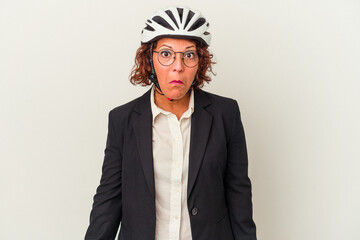 Middle age latin business woman wearing a bike helmet isolated on white background shrugs shoulders and open eyes confused.