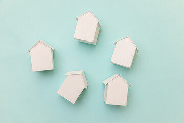 Simply flat lay design with miniature white toy model houses isolated on pastel blue background. Mortgage property insurance dream home concept. Flat lay top view copy space.