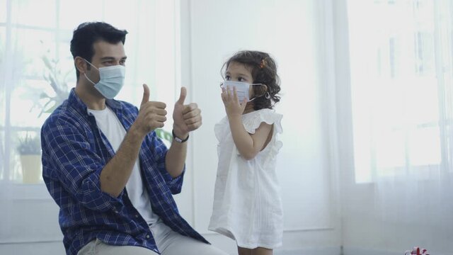 Father helping her daughter to wear a mask, both are wearing face masks for confidence in their health and pouring alcohol hand wash gel to his daughter put on hand to protect her from coronavirus dis