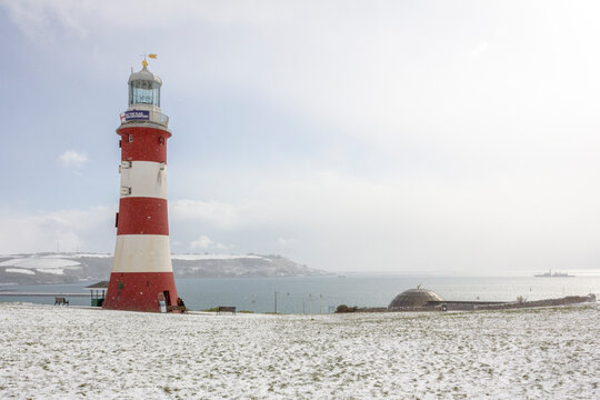 Plymouth Hoe lighthouse on the coast, in the snow