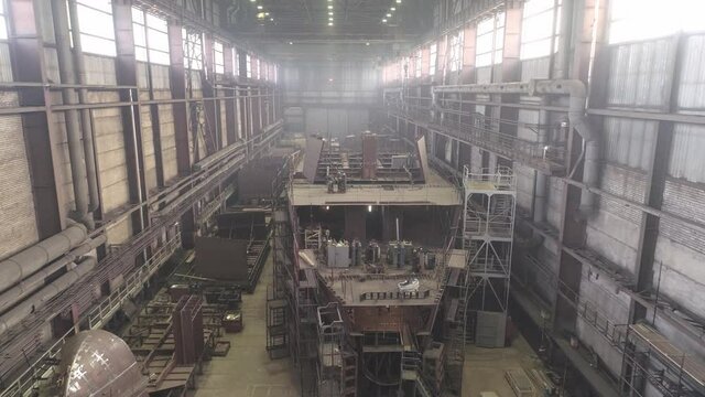 Large old repaired fishing vessel with different equipment on decks and scaffolds stands in dry dock of industrial complex
