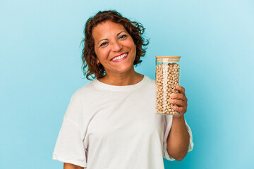 Middle age latin woman holding chickpeas jar isolated on blue background happy, smiling and cheerful.