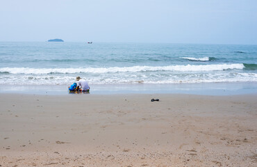 Father and son show a bond with each other. They both sit and have activities together on the seashore.