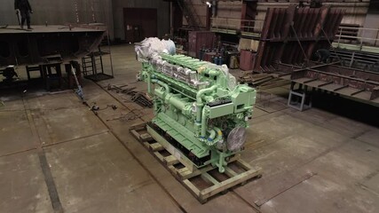 Colorful engine wrapped with foil on floor and worker on repaired crab ship in spacious dry dock at industrial complex