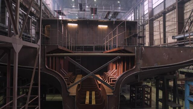 Section of crab vessel with empty hold deck and rust hull in spacious dry repairing dock at industrial complex