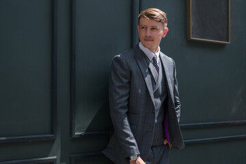 Young man wearing grey suit on the dark-green background . High quality photo