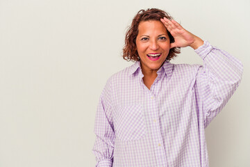 Middle age latin woman isolated on white background shouts loud, keeps eyes opened and hands tense.