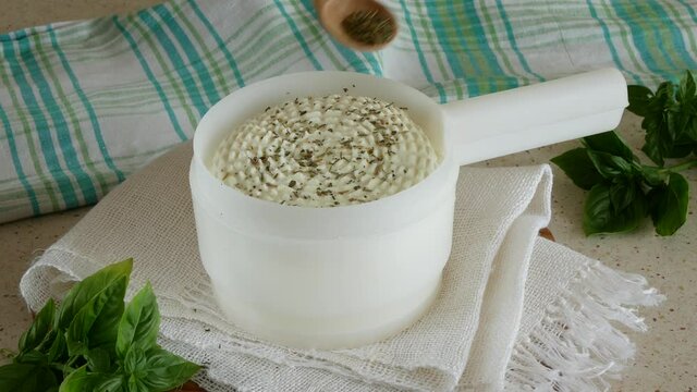 Homemade cottage cheese in the mold is sprinkled with spices. Cheese making process. Healthy organic food