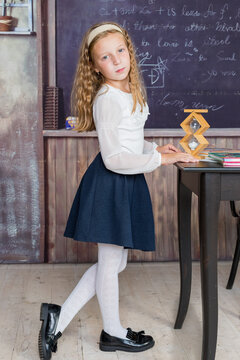 schoolgirl and sandglass in classroom. Small girl in time management concept. education and school concept.manage everything in time.back to school after covid-19 quarantine