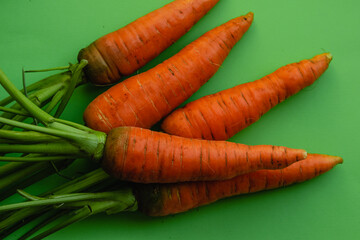 A bunch of fresh ripe orange carrots close-up on a green background.