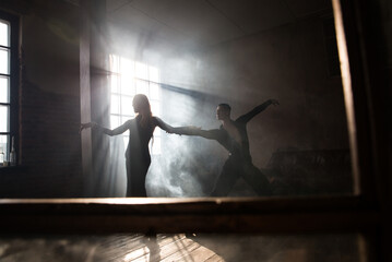 Couple of two professional ballroom dancers is dancing on loft studio. Beautiful art performance with heavy smoke. Sport life concept. Passion and emotional dance.