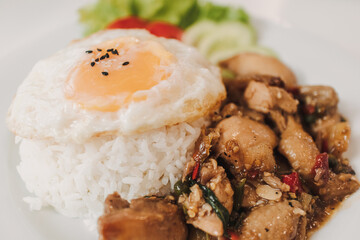 Rice with Basil Fried Chicken and fried egg served on white table.
