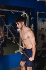 Fototapeta na wymiar Young fitness man pulling the pulley at the gym.