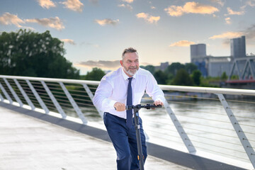 Businessman riding an electric scooter over a bridge