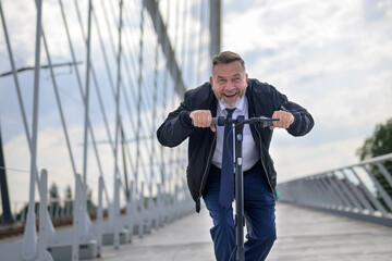 Senior man riding an electric scooter across a bridge