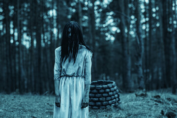 Girl in image of scary zombie walks in dark forest near stone well.