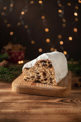 Christmas traditional fruit bread stollen. Christmas cakes. Wooden background. Glittering Christmas decorative light