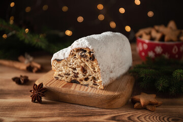 Christmas traditional fruit bread stollen. Christmas cakes. Wooden background. Glittering Christmas decorative light