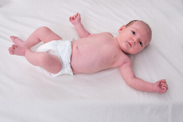 Portrait of a baby boy aged 1 month lying with his eyes open in a crib. Caucasian child in the...