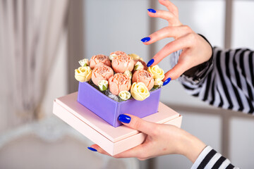 beautiful female fingers hold a rose made of chocolate in square box .depth of field, blur focus