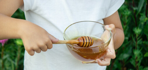child eats honey in the garden.