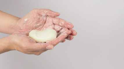 Hands washing gesture with bar soap and foam bubble on white background.