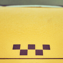 The hood of a yellow taxi car frozen after the first autumn frost with tree leaves