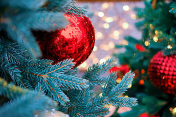 Ornament from red balls, golden garlands bokeh and green christmas tree for the New Year holiday