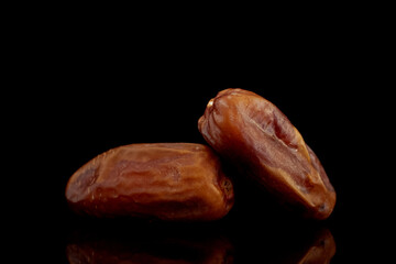 Two dried organic dates, close-up, isolated on black.