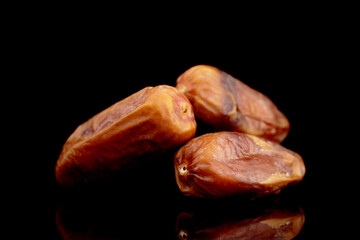 Three dried organic dates, close-up, isolated on black.