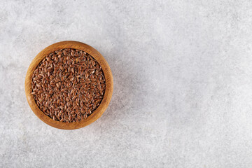 flax seeds in a wooden bowl on a gray stone background. top view