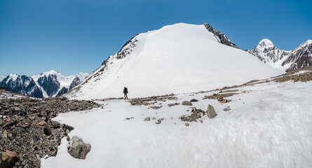 Solo trekking in the mountains. A male hikers down the mountain path. In the background, large...