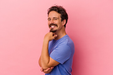 Young caucasian man isolated on pink background smiling happy and confident, touching chin with...