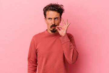 Young caucasian man isolated on pink background with fingers on lips keeping a secret.