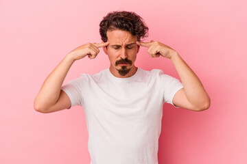 Young caucasian man isolated on pink background focused on a task, keeping forefingers pointing head.