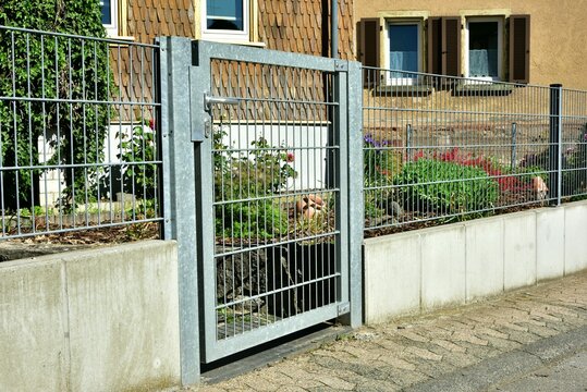Metallzaun mit Gartentor an einem Wohngebäude